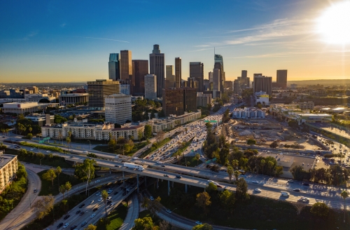 Brummenansicht von im Stadtzentrum gelegenen Los Angeles- oder LA-Skylinen mit Wolkenkratzern und Autobahnverkehr unten.