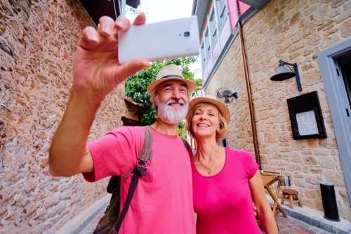 Tourismus und Technologie. Reisende ältere Paare, die zusammen selfie gegen alten Stadthintergrund nehmen.