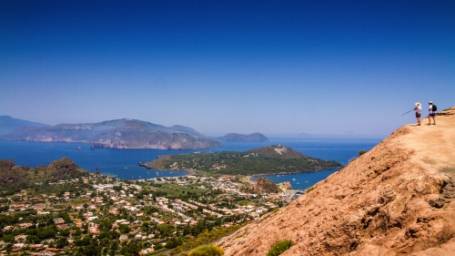 Zwei nicht wiedererkennbare Wanderer genießen vom Vulkankraterrand des Fossa di Vulcano aus den Blick über die Äolischen Inseln