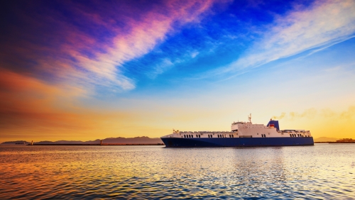 Ro Ro-Frachtschiff, das den Hafen bei Sonnenuntergang verlässt