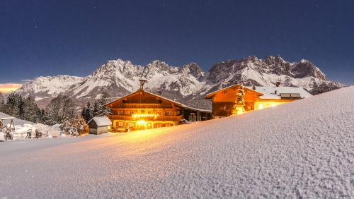 schön beleuchteter Bauernhof mit dem Wilden Kaiser im Hintergrund