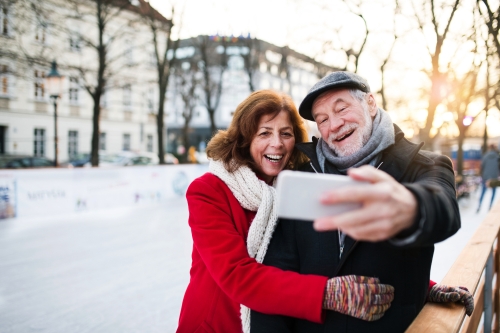 Senior couple with smartphone on a walk in a city in winter.~1