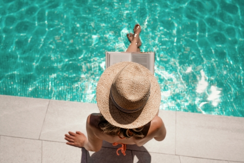 Frau am Pool liest Buch