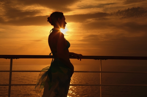 woman standing on deck of cruise ship and looking away.