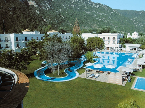 Mitsis Galini - Hotelanlage mit Pool, Liegen und Sonnenschirmen, umgeben von grüner Landschaft und Gebäuden.