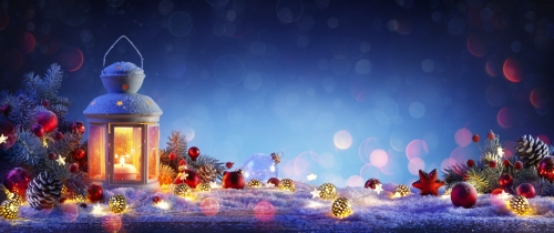 Weihnachtslaterne auf schneebedecktem Tisch mit Tannenzweigen und Verzierungen