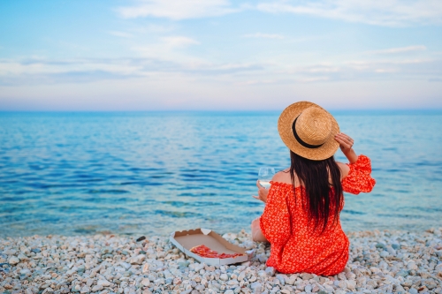 Frau, die ein Picknick mit Pizza am Strand macht