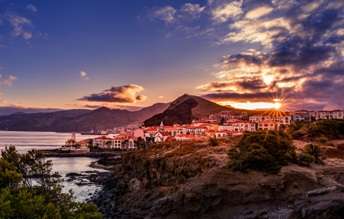 View on village with coastline during sunset with sun star