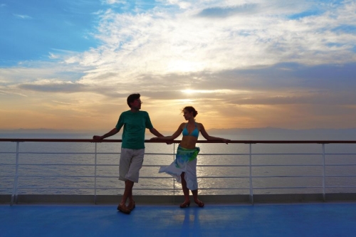 man and woman standing on deck of cruise ship.