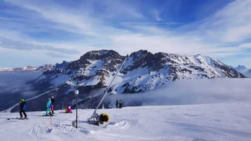 Aussicht auf verschneite Berge, Skifahrer und Wolken im Skizentrum Latemar, Italien