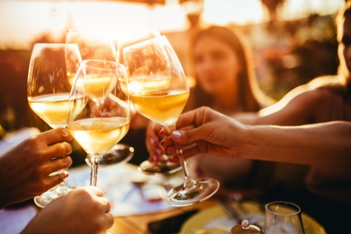 Menschen, die auf der Sommerterrasse eines Cafés mit Weingläsern anstoßen 