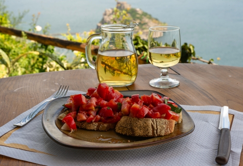 Italienische Bruschetta und Weißwein vor dem Hintergrund der aragonesischen Burg auf der Insel Ischia, Italien