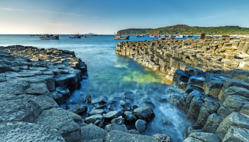 Exposure Wellen im Giants Causeway Morgendämmerung, Fischerboote sind immer noch wach. Giants Causeway ist der Staat als nationale Szenerien anerkannt