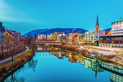 Blick auf einen Flussufer der Drau bei Sonnenuntergang in Villach, Österreich