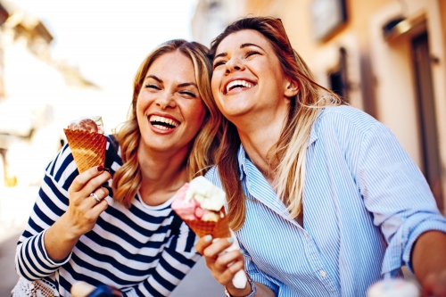 Zwei junge Frauen, die in der Hand Eiscreme lachen und halten
