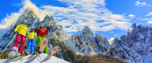 Skiing family enjoying winter vacation on snow in sunny cold day in mountains and fun. San Martino di Castrozza, Italy.